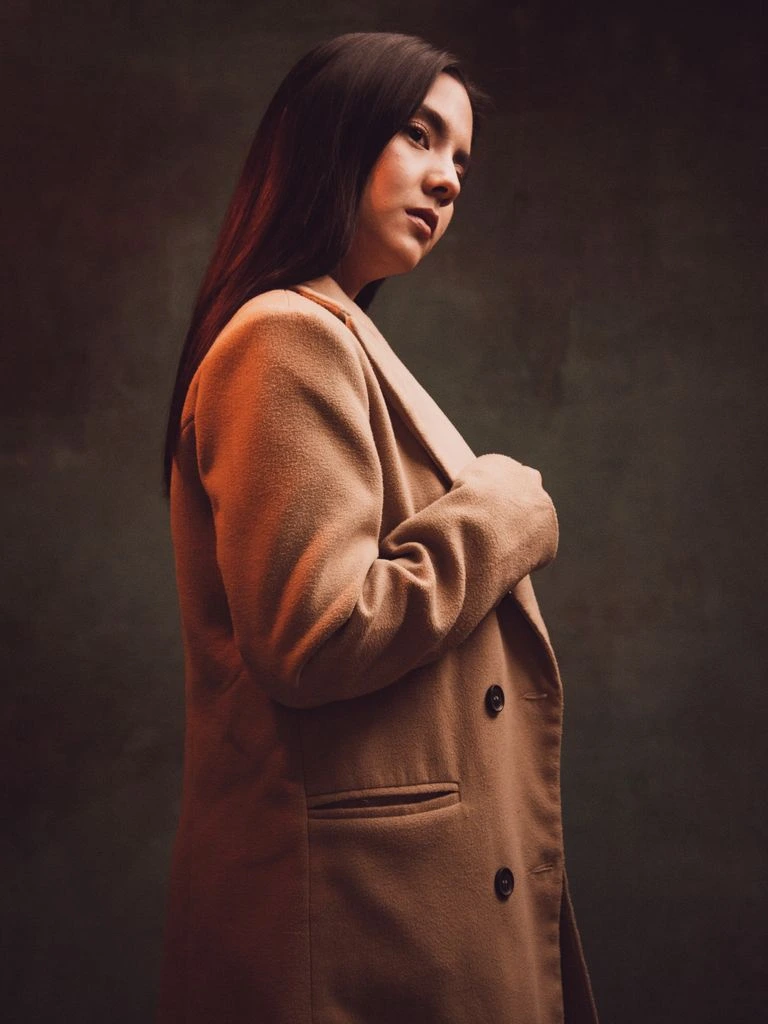An on-air host seated beside a vintage Neumann microphone in a wood-paneled broadcast studio.